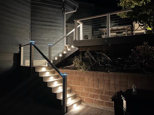 Lit up staircase leading up to a wooden deck with seating